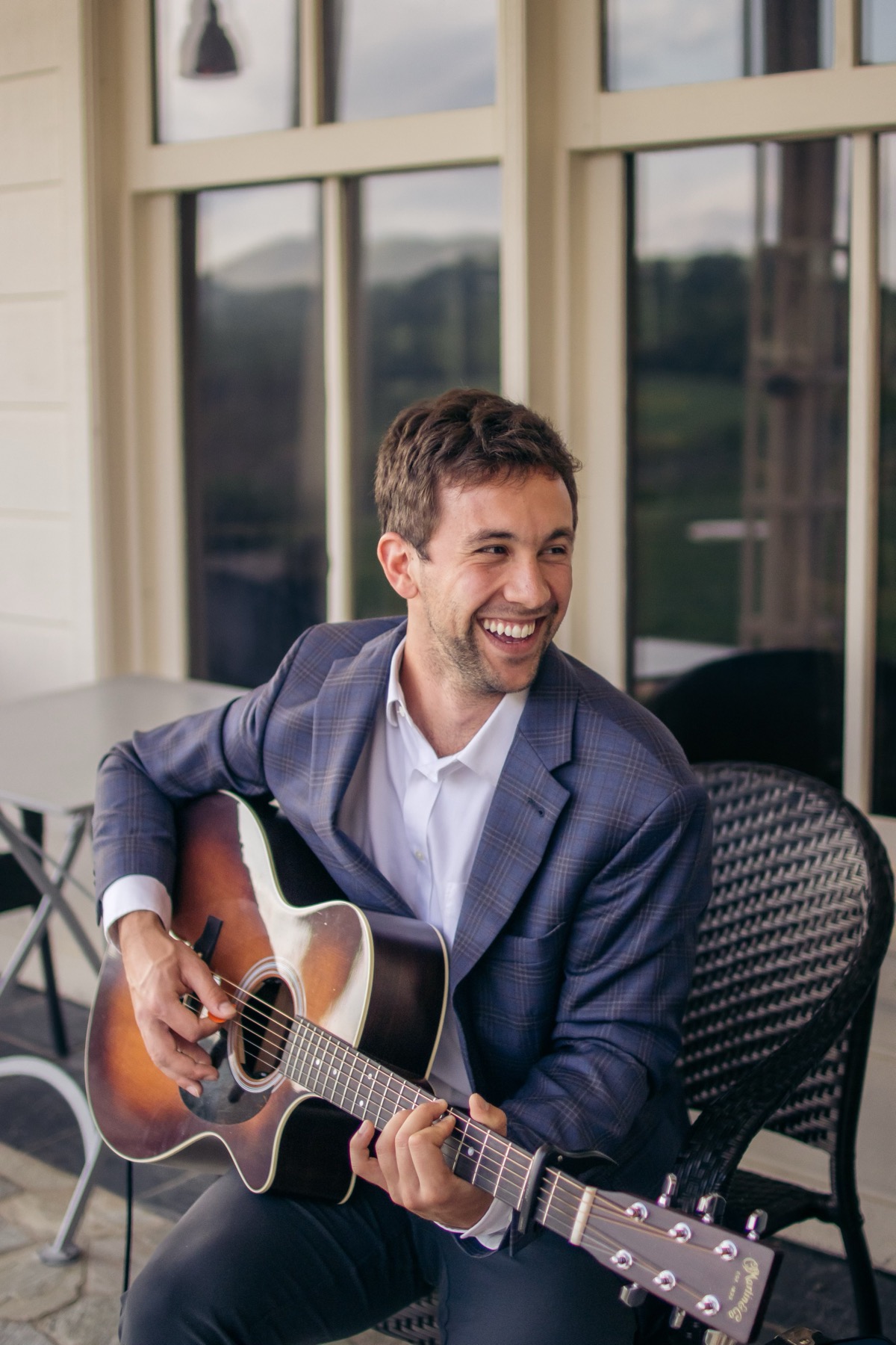 Donovan Fiore laughing, playing an acoustic guitar on a porch